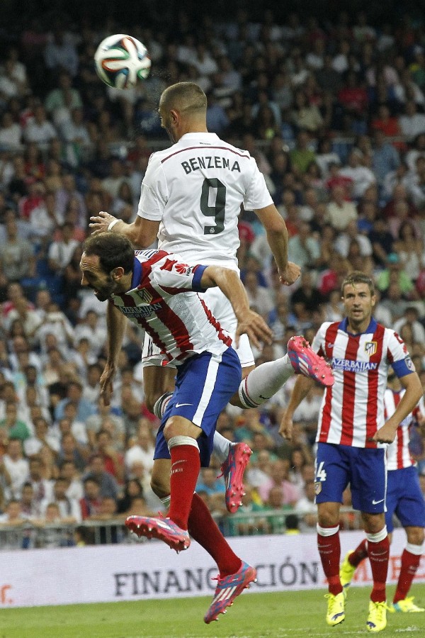El delantero francés del Real Madrid Karim Benzema (d) salta por el balón con Juanfran, del Atlético de Madrid, durante el partido de ida de la Supercopa de España.