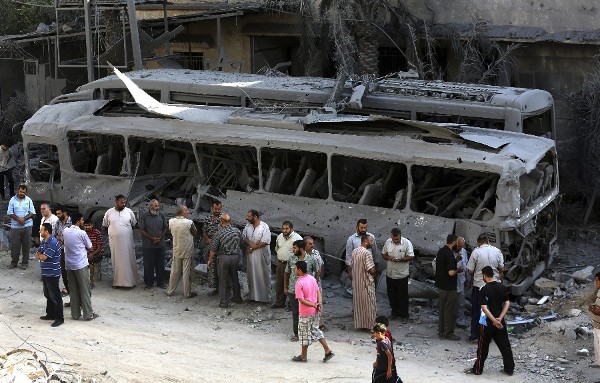 Palestinos inspeccionan un autobús destrozado tras un ataque aéreo israelí en respuesta a varios cohetes lanzados desde Gaza horas antes del fin de la tregua en Gaza hoy, miércoles 20 de agosto de 2014.