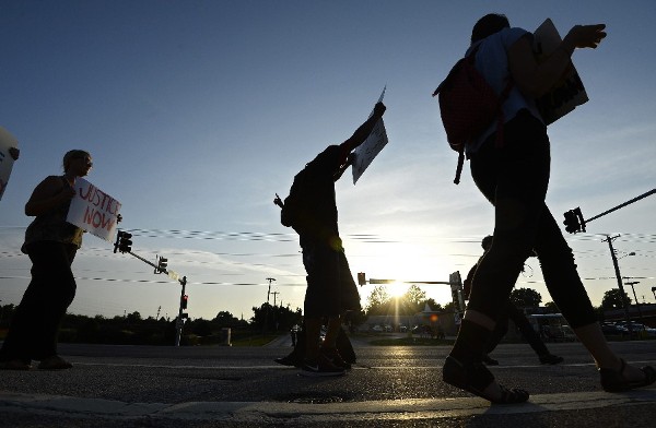 Manifestantes caminan por una calle para protestar por el asesinato de Michael Brown el miércoles 20 de agosto de 2014, en Ferguson, Misuri.