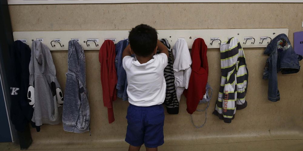 Un niño coloca su prenda de vestir en un aula.