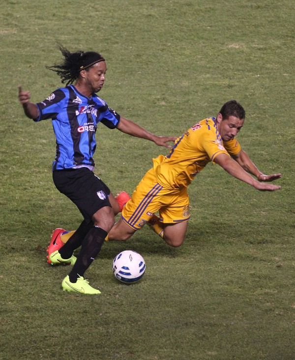 El brasileño Ronaldinho (i) del Querétaro disputa el balón con Jesús Alberto Dueñas (d) de Tigres.