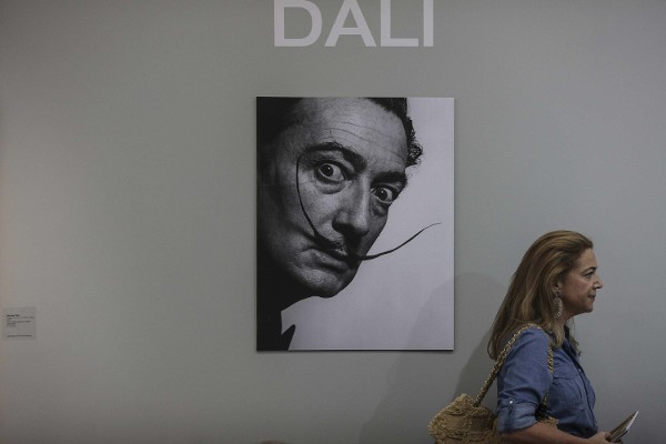 Una mujer camina frente a una fotografía de Salvador Dalí.