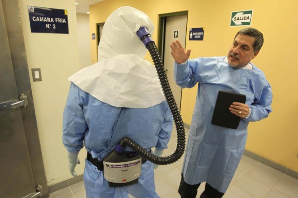 El Jefe del Instituto Nacional de Salud de Perú, Ernesto Bustamante (d), muestra los trajes utilizado para atender eventuales casos de ébola.