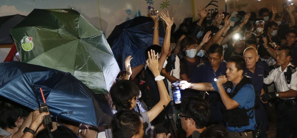 Policías de Hong Kong (d) armados con gases intentan hacer retroceder a manifestantes del movimiento Occupy Central.