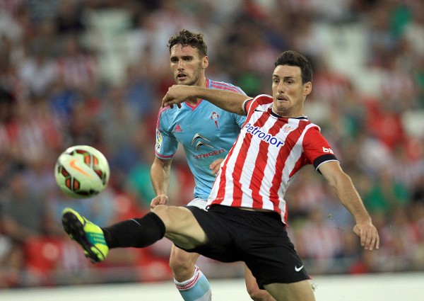 El delantero del Athletic de Bilbao Aritz Aduriz (d) remata ante el defensa del Celta de Vigo Sergi Gómez en partido de liga de Primera División correspondiente a la octava jornada disputado en el campo de San Mamés.