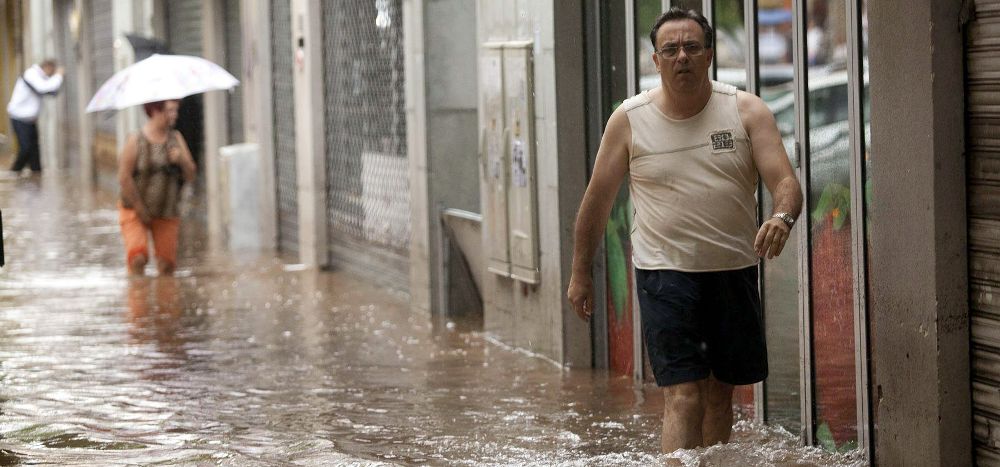 Un hombre camina por una de las calles de Santa Cruz de Tenerife inundadas a consecuencia de la tromba de agua que ha caído en las últimas horas.