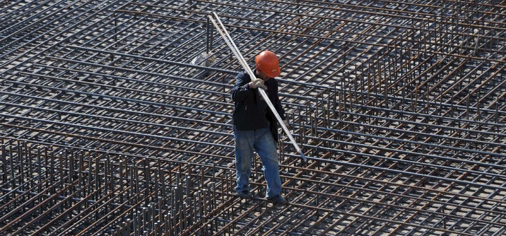 Un trabajador carga con barras de acero en una obra en Shenyang.