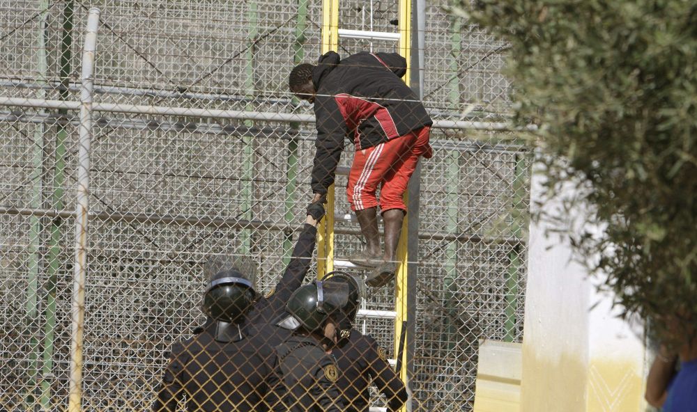 Varios de los inmigrantes de origen subsahariano encaramados desde primera hora de esta mañana a la valla de Melilla, bajan tras permanecer en lo alto alrededor de seis horas.