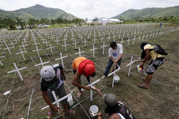 Trabajadores colocan cruces de madera en una fosa común que alberga los cuerpos de 3.000 víctimas del tifón, en Tacloban (Filipinas).