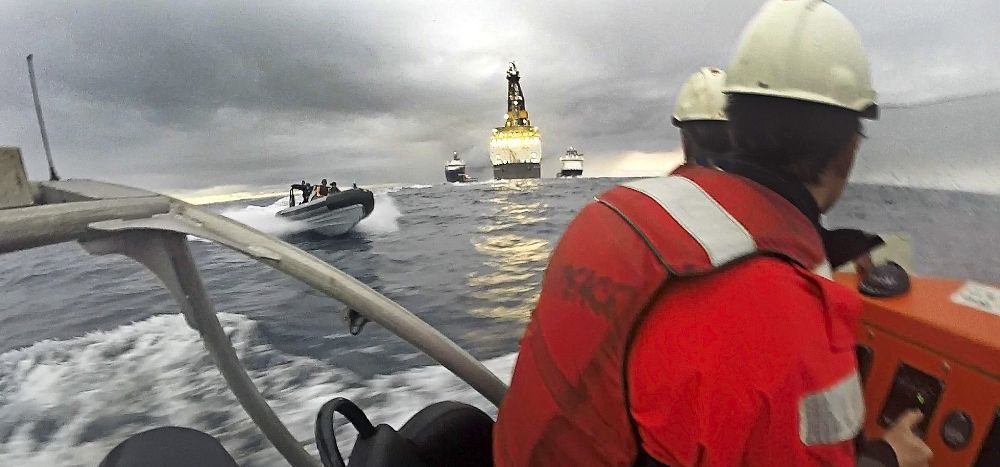 Fotografía facilitada por Greenpeace de dos activistas en una de sus lanchas y otra de la Armada española acercándose por la izquierda.