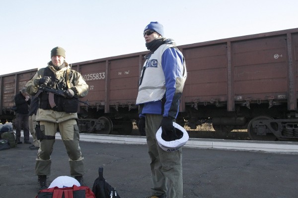 Un miembro de la OSCE junto a un hombre armado.