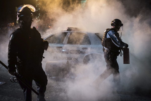 Un policía intenta apagar el fuego en un vehículo policial aparcad ante el edificio del ayuntamiento en Ferguson.
