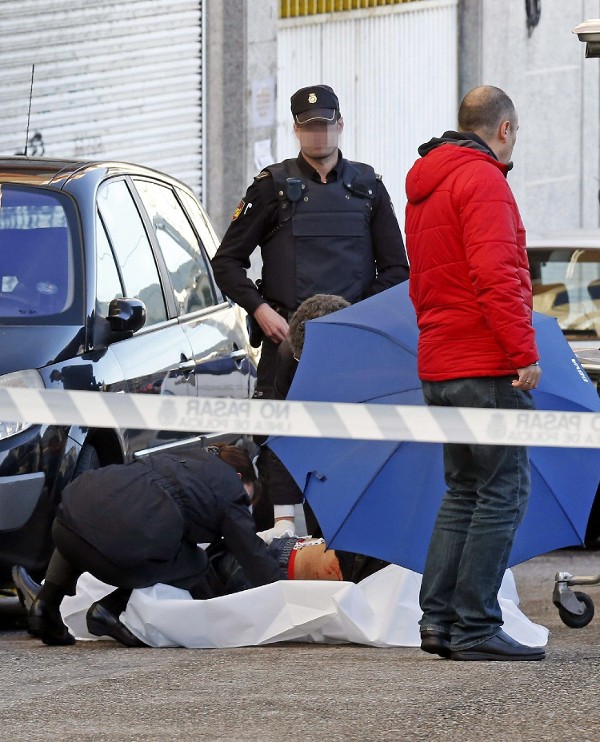 Efectivos de la Policía junto al cuerpo del atracador fallecido en el atraco hoy a una entidad bancaria de Vigo. 