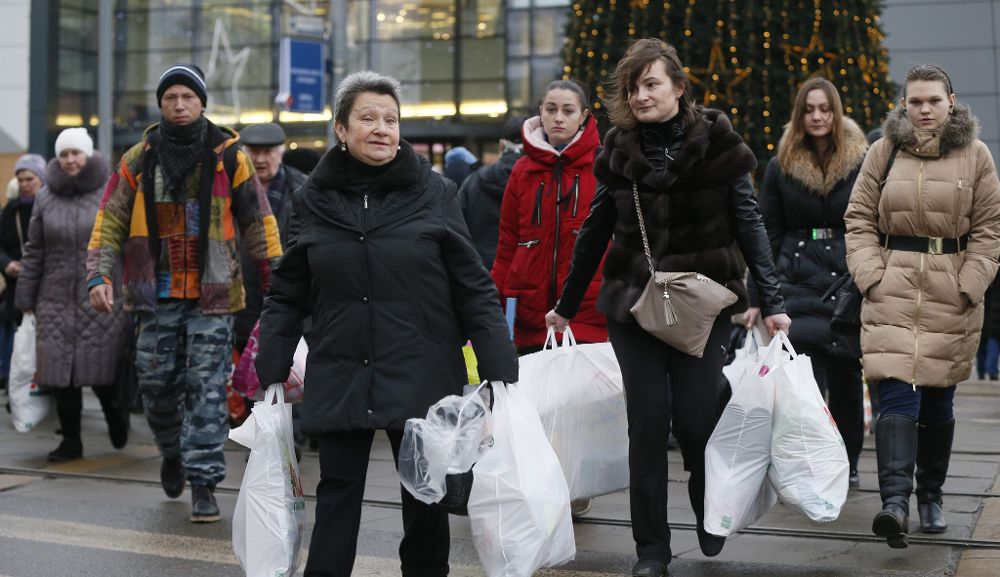 Varias moscovitas cruzan una calle cargadas de bolsas en Moscú hoy, miércoles. El Ministerio de Finanza de Rusia anunció hoy que comenzará a vender sus remanentes de divisas en el mercado para respaldar la moneda nacional, el rublo.