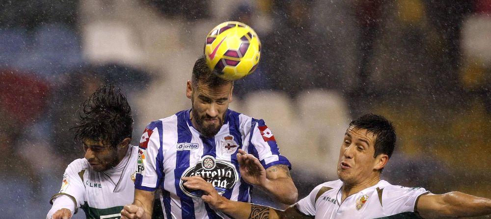 El defensa del Deportivo, Alberto Lopo (c), cabecea un balón.