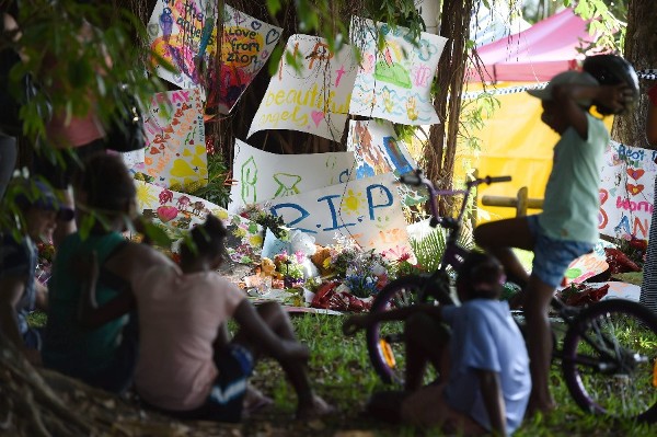 Varios niños junto a las flores y mensajes en recuerdo de los niños asesinados.