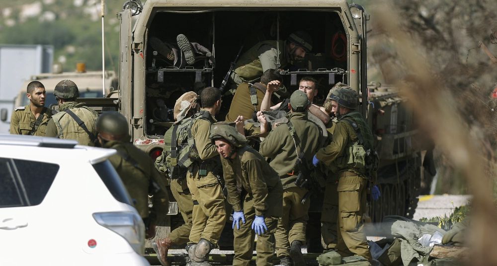 Varios soldados israelíes evacúan a un compañero herido después de que impactara un misil antitanques en su vehículo cerca de la zona de Har Dov, en la frontera entre Israel y el Líbano hoy.