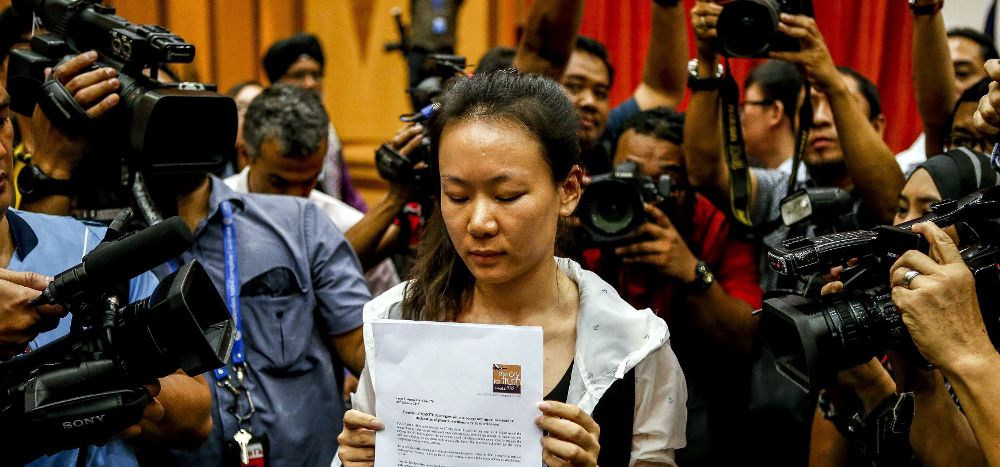 La mujer de uno de los viajeros del vuelo de Malaysian Airlines MH370 muestra una proclama escrita durante una rueda de prensa en Putrajaya (Malasia).