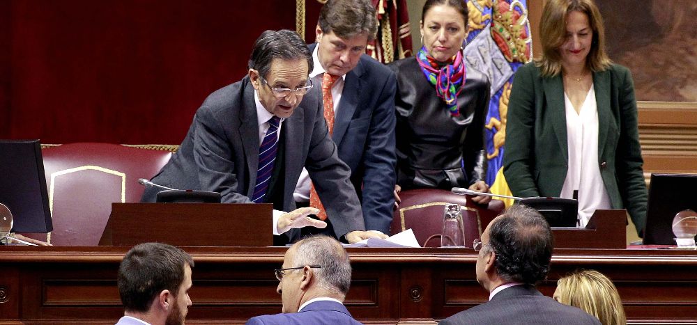 El presidente del Parlamento de Canarias, Antonio Castro (i), conversa con los miembros de la Mesa y los portavoces parlamentarios antes de comenzar la sesión plenaria de hoy.