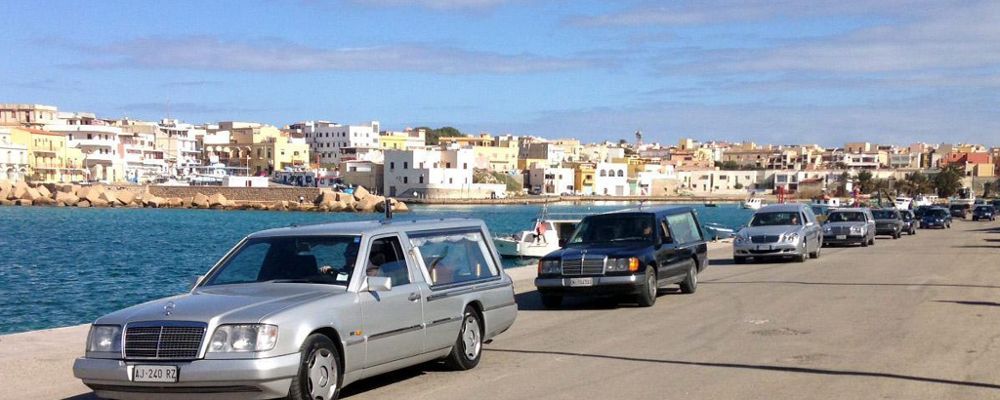 Varios coches fúnebres transportan los cadáveres de inmigrantes en el puerto de Lampedusa.