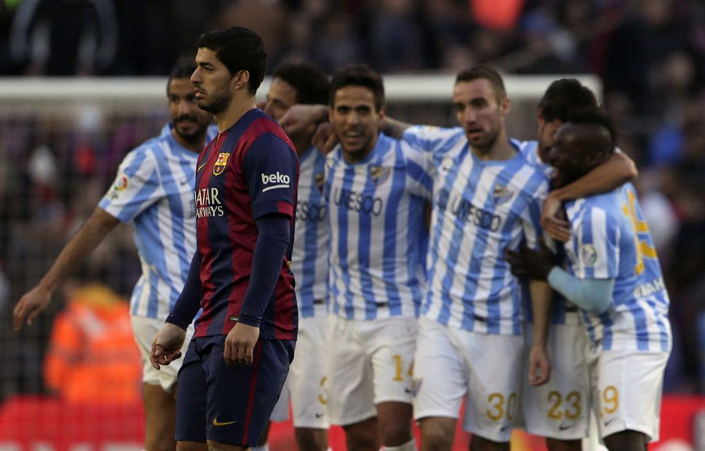 Los jugadores del Málaga celebran su victoria, ante el delantero Luis Suárez.