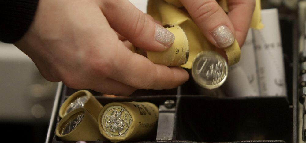 Un cajero coloca monedas de un euro en su caja.