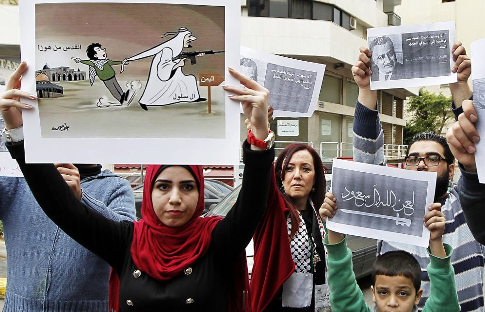 Varias personas sostienen carteles que rezan "Dios maldice a Arabia Saudí" durante una protesta en contra de los bombardeos perpetrados en Yemen por la coalición liderada por Arabia Saudí, a las puertas de la embajada saudí en Beirut, Líbano.