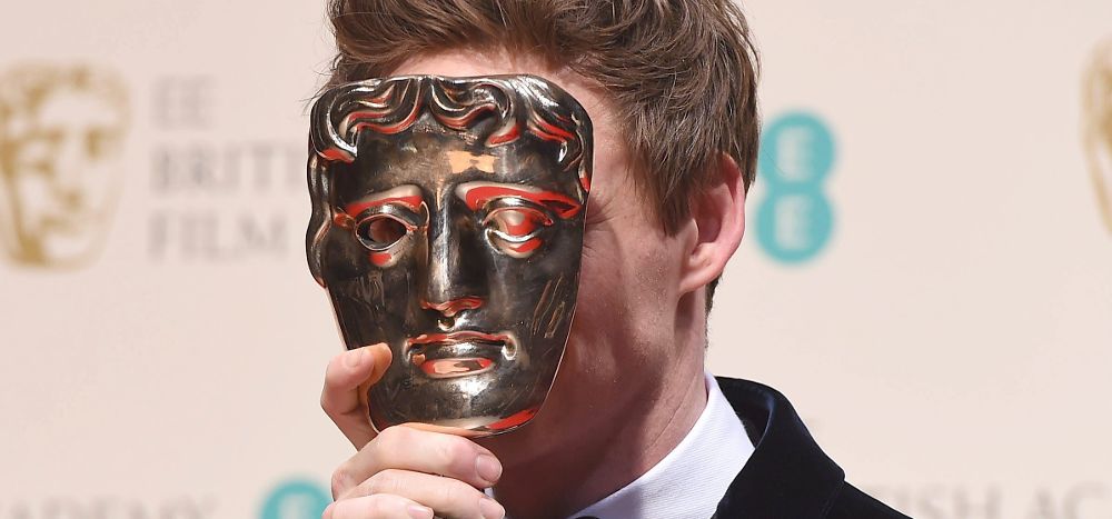 Tapándose la cara con el BAFTA a mejor actor.