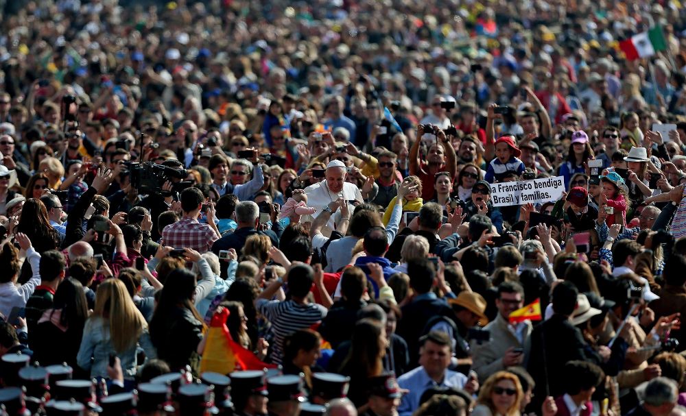 El papa Francisco (c) acaricia a un bebé entre los miles de feligreses congregados en la Plaza de San Pedro para asistir a su audiencia general de los miércoles, en la Ciudad del Vaticano.