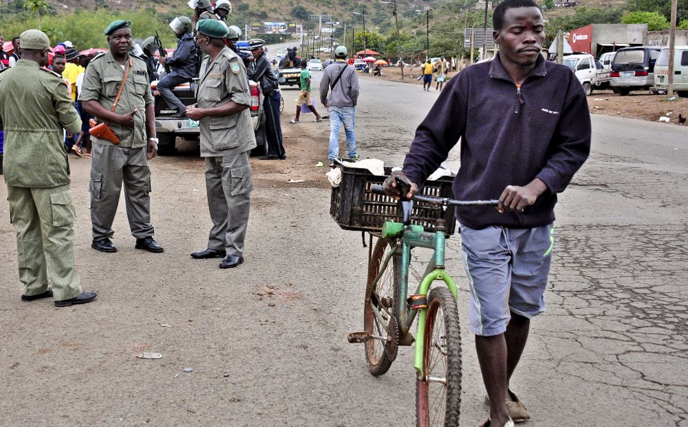 Varios policías vigilan a unos trabajadores, que bloquean la carretera limítrofe con Sudáfrica de Moamba, Mozambique, que ha cerrado parte de su frontera terrestre con Sudáfrica tras los disturbios.