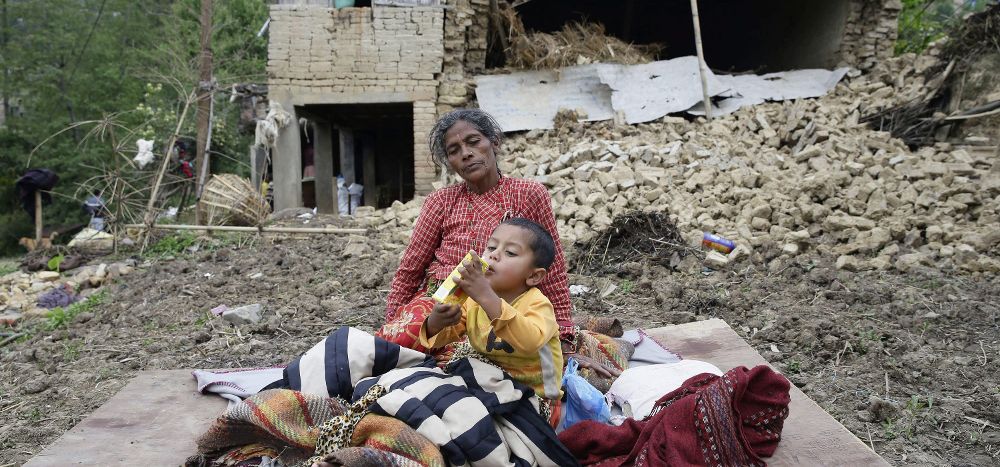 Varias personas permanecen junto a sus hogares destruídos.