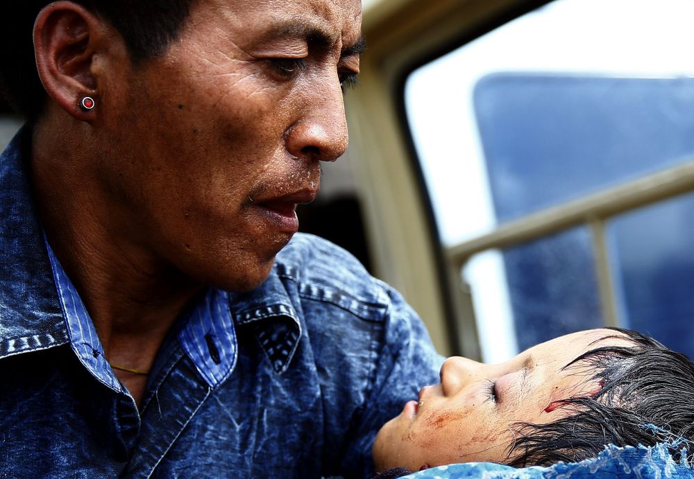 Un padre sostiene a su hijo herido mientras ambos son evacuados a la base militar de Chautara en espera de ser enviado al hospital de Katmandú.
