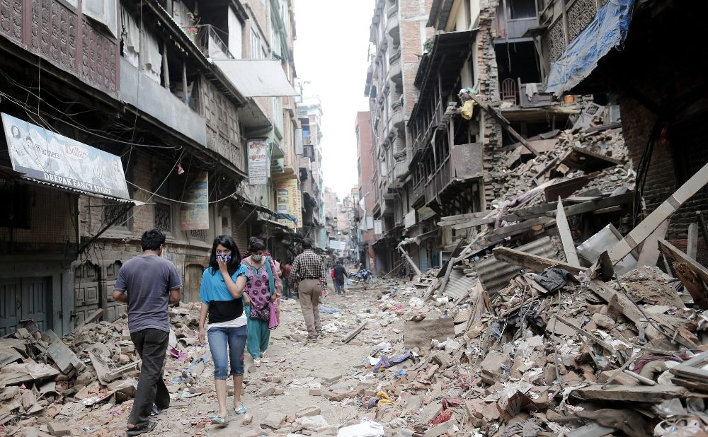 Gente caminando entre los edificios derruidos en una calle de Kathmandú.