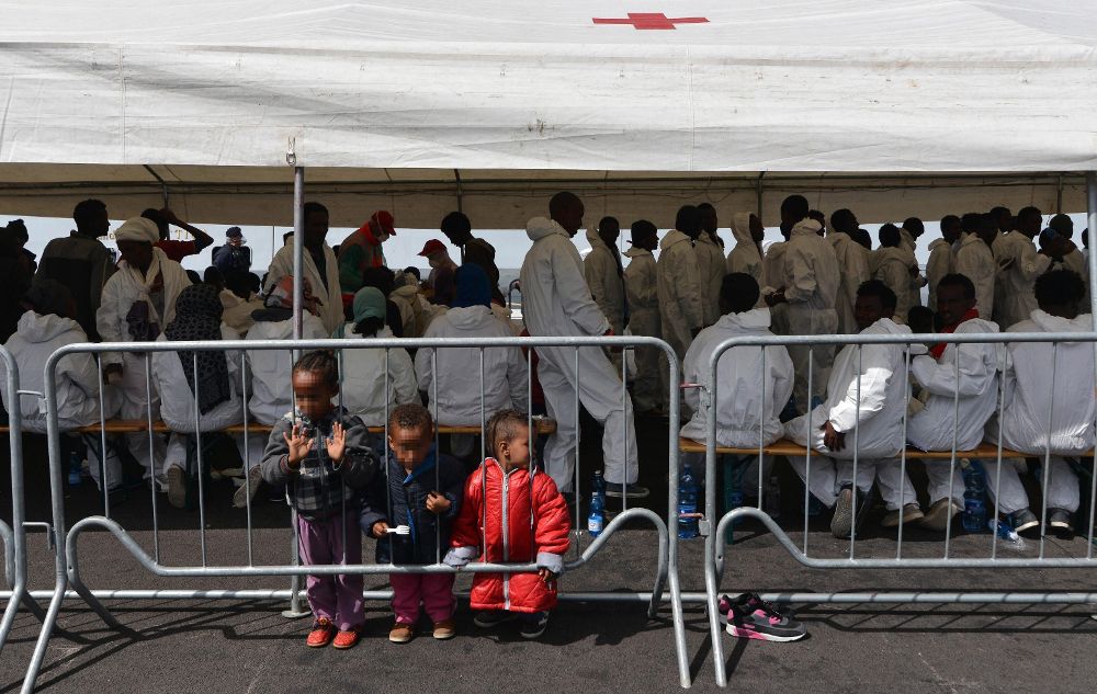 Un grupo de inmigrantes descansa bajo una carpa de la Cruz Roja después de desembarcar en el puerto de Salerno, Italia, hoy.