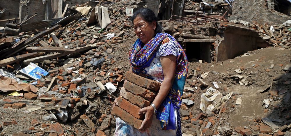Una superviviente nepalesa recupera ladrillos de entre las ruinas.