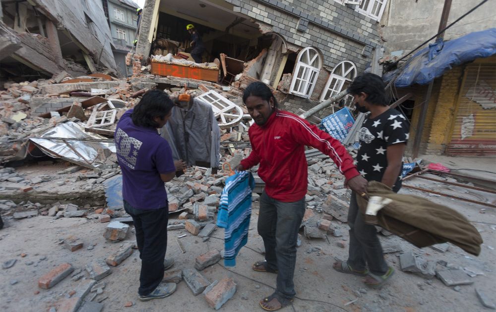 Varias personas recogen lo que queda de sus pertenencias de entre los emcombros causados el terremoto en Katmandú.