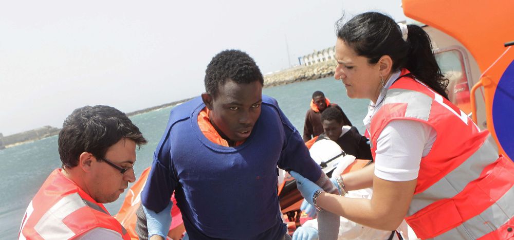 Personal de Cruz Roja ayuda a desembarcar a un inmigrante subsahariano.