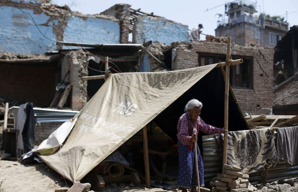 Una superviviente de avanzada edad junto a una tienda de campaña improvisada en una zona devastada en Bungamati (Nepal).
