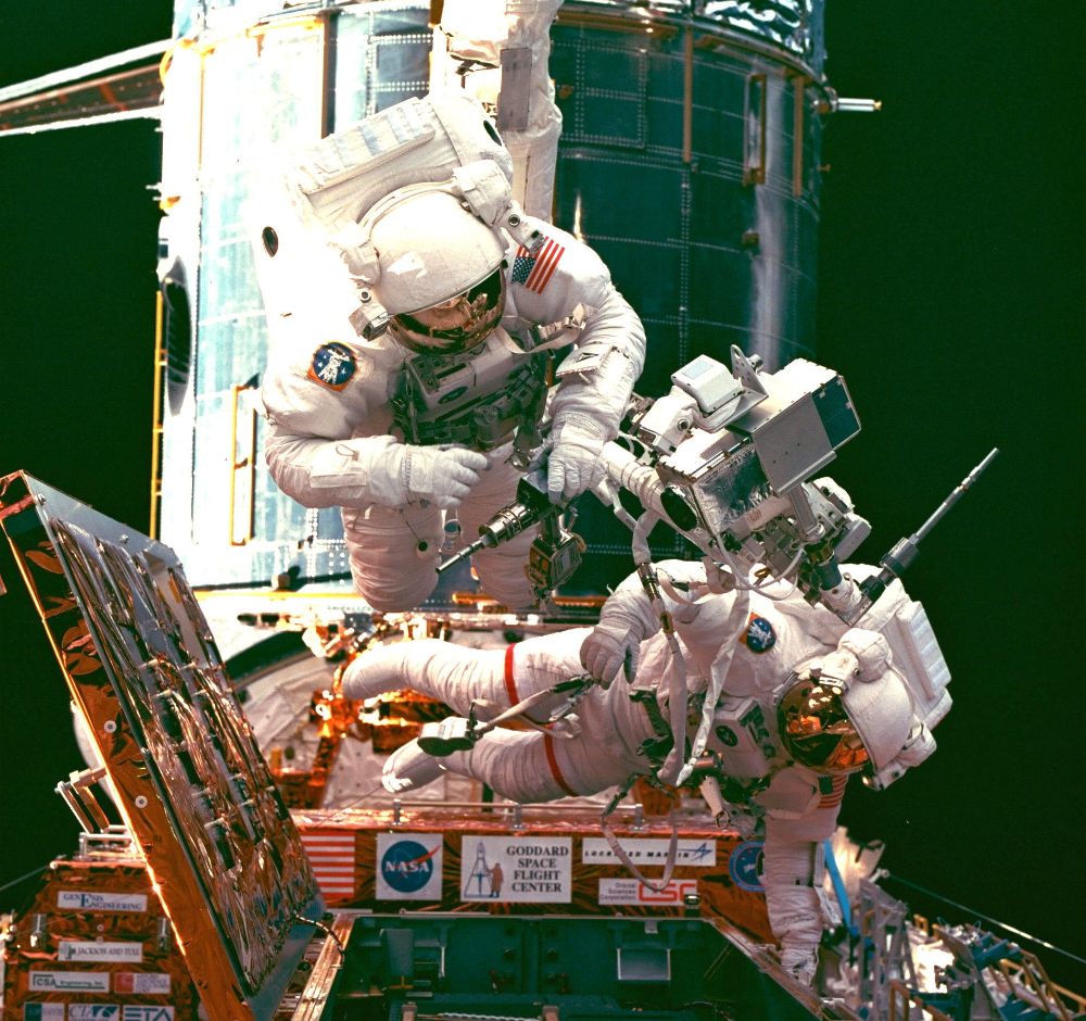 Dos astronautas en un momento de la reparación del telescopio espacial Hubble, un ingenio que cumple un cuarto de siglo fotografiando los rincones más remotos del firmamento. 
