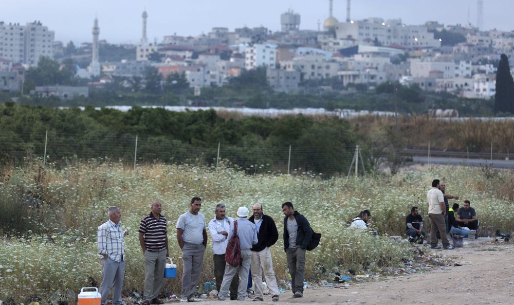 Trabajadores palestinos esperan la llegada de su autobús en el paso israelí de Eyal tras cruzar al país desde la localidad cisjordana de Qalqilya.