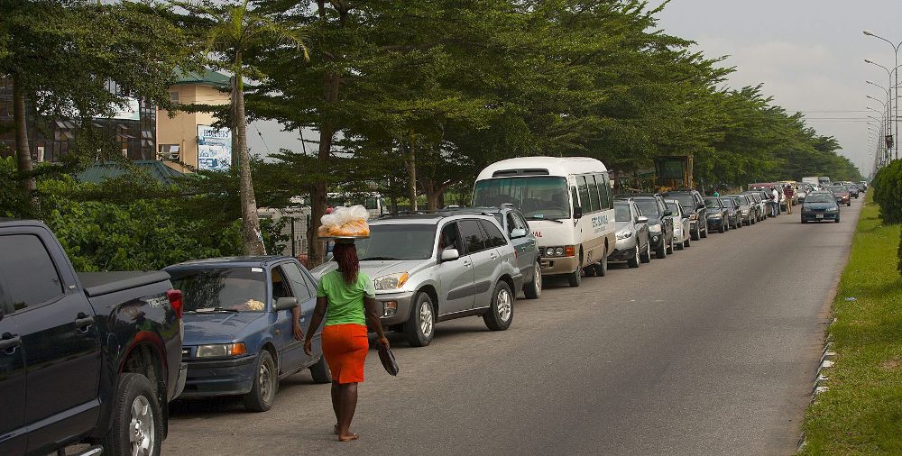 Una mujer vende frutas junto a una fila de vehículos a las afueras de una estación de servicio en el estado de Bayelsa (Nigeria). Las grandes colas obedecen al racionamiento.