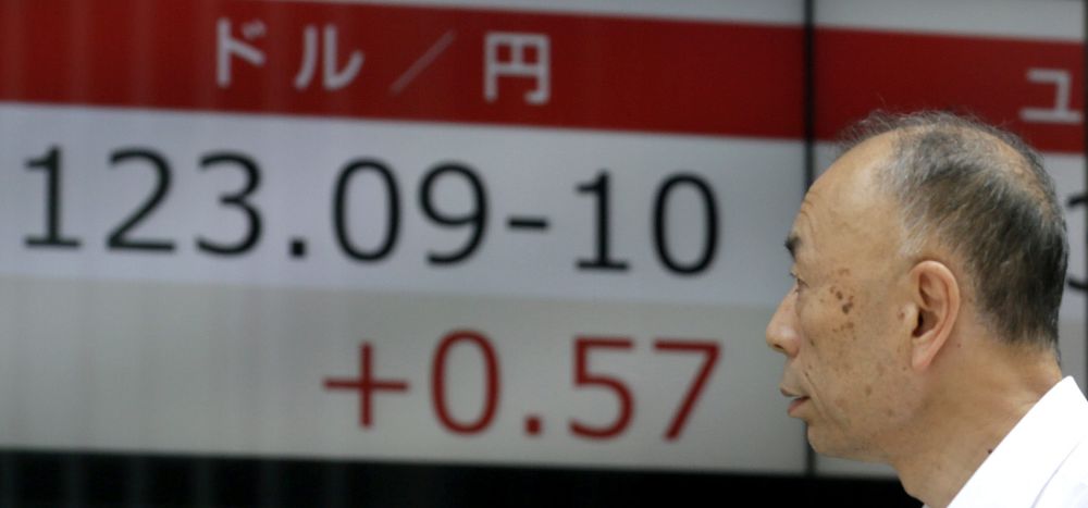 Un hombre pasa delante de una pantalla con el valor de cambio del yen respecto al dólar.