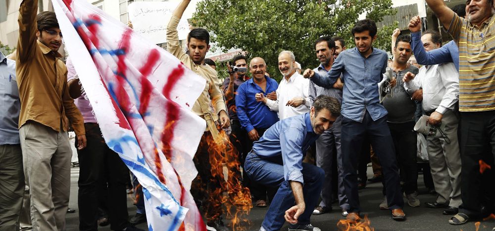 Varios iraníes queman banderas estadounidenses e israelíes en respuesta a las exigencias occidentales en la negociación sobre armamento nuclear.