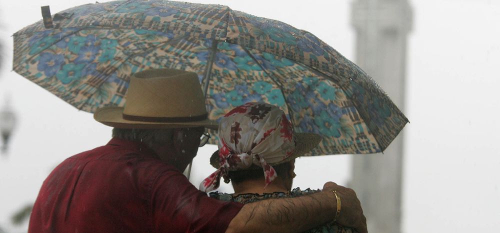 Una pareja se protege de la lluvia hoy en las inmediaciones de la Plaza de la España de Santa Cruz de Tenerife,