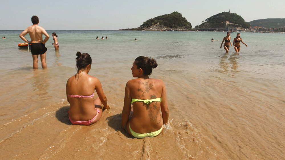 Donostiarras y visitantes disfrutan en la playa de Ondarreta de San Sebastián de los cielos despejados y las altas temperaturas que han superado los 35 grados en las horas centrales del día.