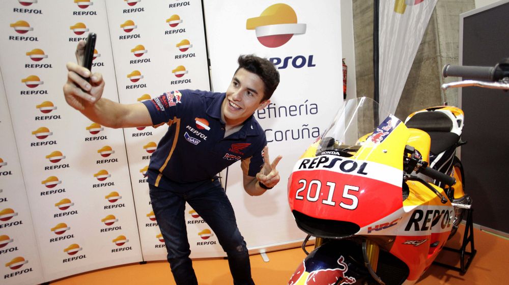 El piloto Marc Márquez se hace una foto con la moto campeona del pasado mundial de MotoGP.