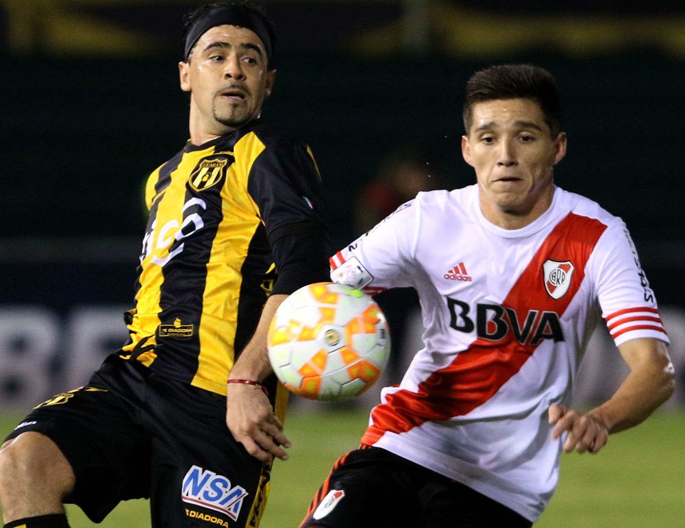 El jugador de Guaraní Rubén Maldonado disputa el balón con Matías Kranevitter (d), de River Plate.