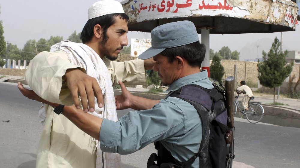 Un oficial de seguridad afgano cachea a un hombre en la ciudad de Kandahar.