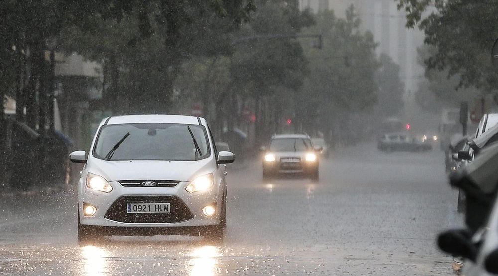 Varios vehículos circulan bajo la lluvia.
