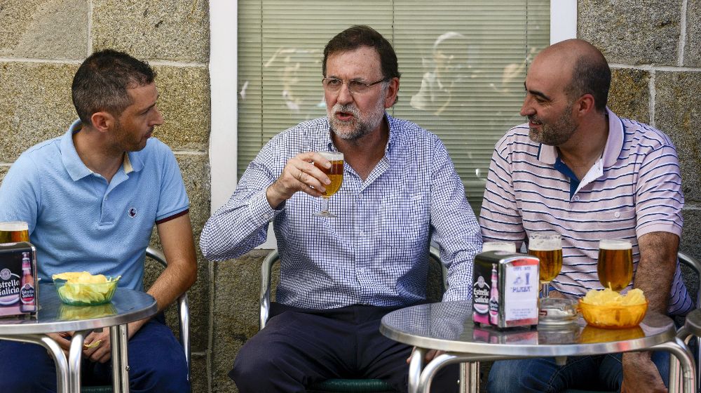 El presidente del Gobierno, Mariano Rajoy (c), que se encuentra de vacaciones en Galicia, toma una caña con el alcalde de Celanova (Ourense), José Luis Ferro (d), en un bar de la plaza mayor de esta localidad.